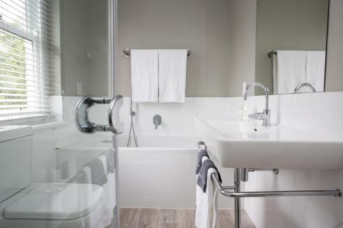 a white bathroom with a sink and a tub at Summerwood Guest House in Stellenbosch