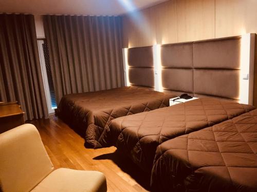 una habitación de hotel con 2 camas y una silla en Hotel Europa en Vila Pouca de Aguiar