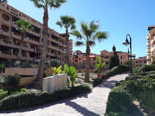 una pasarela frente a un edificio con palmeras en Apartamentos Turísticos Spiritmar, en Almerimar