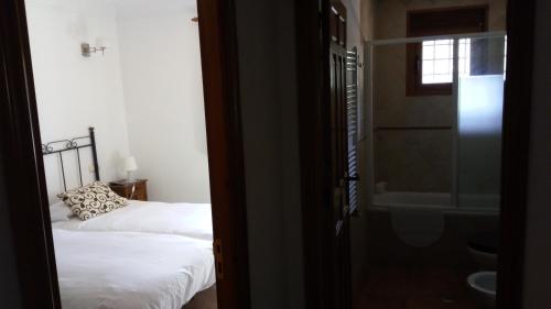 a bedroom with two beds and a bathroom with a window at Casa Rural Mirabueno in Cuenca