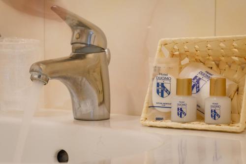 ein Waschbecken mit einem Wasserhahn und einer Flasche Zahnpasta in der Unterkunft Hotel Duomo in Siena
