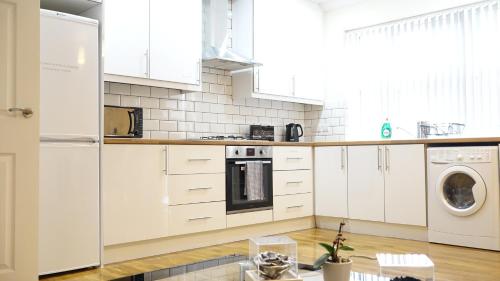 a kitchen with white cabinets and a washer and dryer at Heathrow Ensuite Rooms in Stanwell