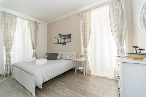 a white bedroom with a bed and large windows at Appartamento Ponte Lungo in Rome