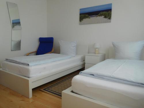 a bedroom with two beds and a blue chair at Arkadia Hotel in Burgwedel