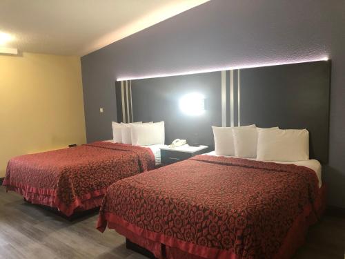 a hotel room with two beds with red sheets at Days Inn by Wyndham Grove City Columbus South in Grove City