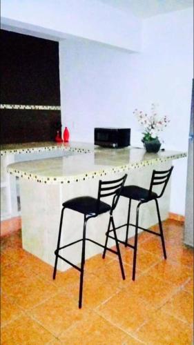 - une cuisine avec 2 chaises et un comptoir blanc dans l'établissement casa cómoda y céntrica, à Tuxtla Gutiérrez