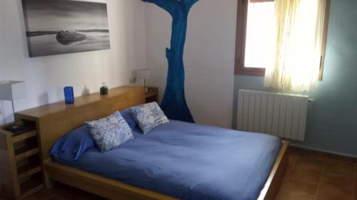 a bedroom with a bed with blue sheets and a tree at Casa Rural Mirabueno in Cuenca