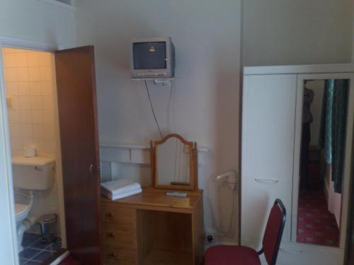 a bathroom with a vanity with a mirror and a tv on the wall at Stanley House Hotel in London