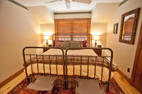 ein Schlafzimmer mit einem Metallbett mit zwei Stühlen in der Unterkunft Penthouse By The Gondola in Telluride