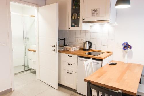 a kitchen with white cabinets and a wooden table at Koper2stay in Koper