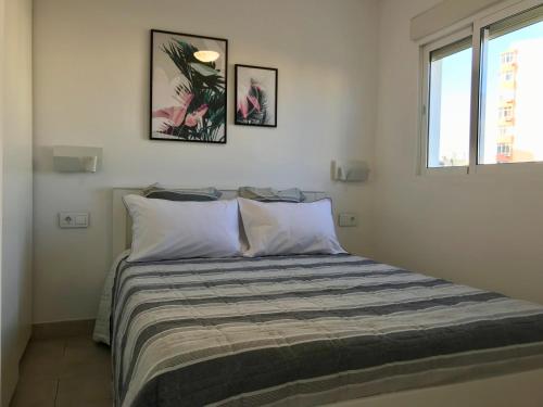 uma cama num quarto com duas fotografias na parede em Apartamento Sol y Mar em Torremolinos