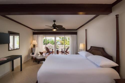 1 dormitorio con 1 cama blanca y comedor en Cofresi Palm Beach & Spa Resort - All Inclusive en San Felipe de Puerto Plata