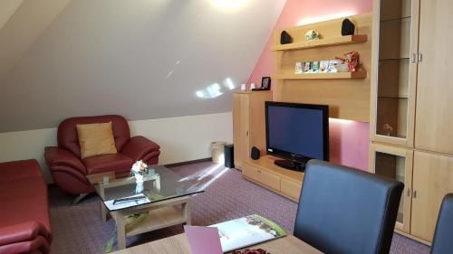a living room with a tv and a table and chairs at Hotel Rhöner Land Garni - Bed & Breakfast in Oberthulba