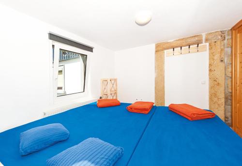 Habitación con cama grande azul con cojines de color naranja. en Bergoase Hütte und Hostel Sauna Kamin Lagerfeuer, en Mittelndorf