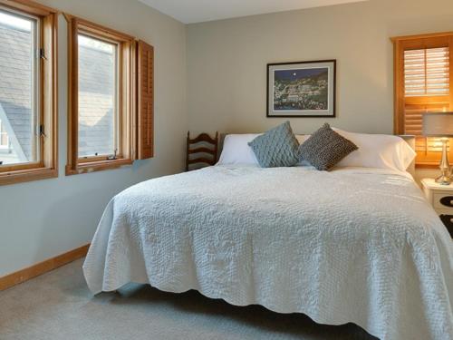 a bedroom with a white bed with two windows at River Bluff Farm Bed and Breakfast in Quicksburg