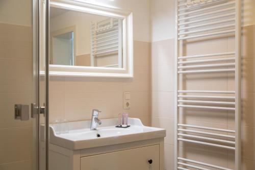 a bathroom with a sink and a mirror at Heeren's Hotel Garni in Bensersiel