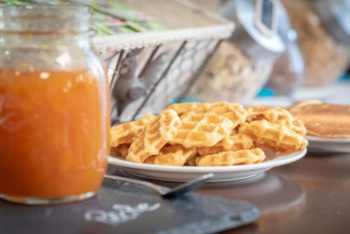 a plate of waffles on a plate with a jar of honey at Sure Hotel by Best Western Beziers Le Monestie in Béziers