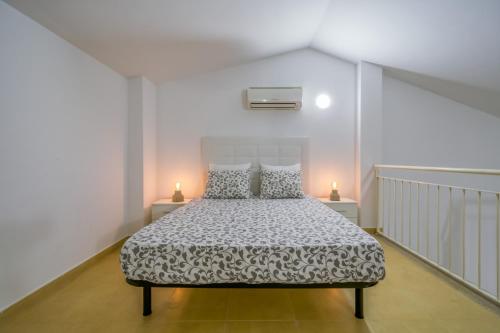 a bedroom with a bed in a white room with two lamps at Vivalidays Urban Tossa House in Tossa de Mar