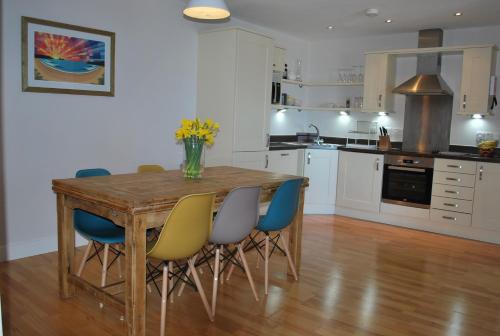 a kitchen with a wooden table and blue chairs at For the Shore, Fistral Beach Newquay - 2 Bed 2 bath - Private Parking with garage for 2 vehicles in Newquay