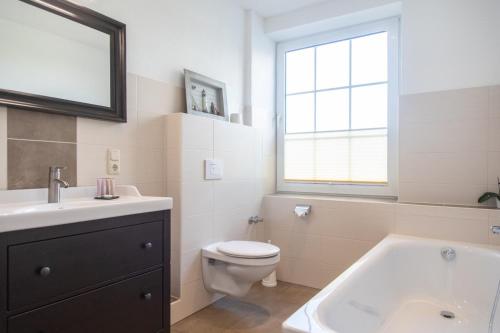 a bathroom with a toilet and a sink and a tub at Heeren's Hotel Garni in Bensersiel