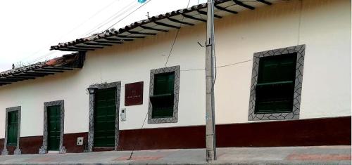 a white building with green windows and a pole at Casa Vieja Posada in Pesca