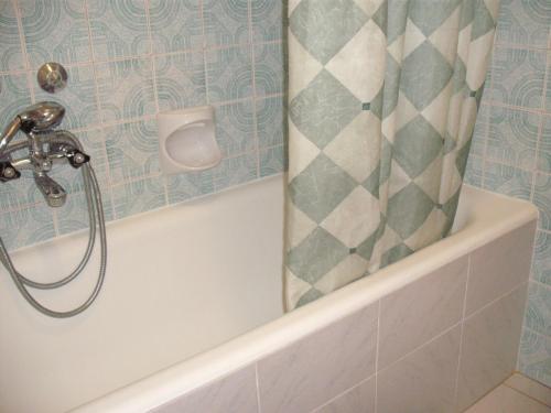 a bath tub with a shower curtain in a bathroom at Apart Hévízi Ház in Hévíz