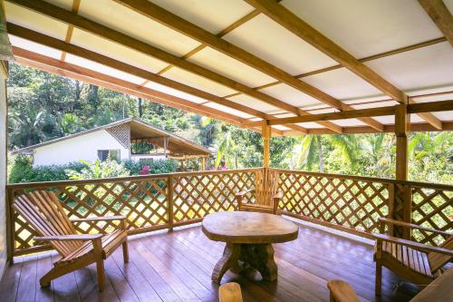 a wooden porch with a table and chairs on it at Passion Fruit Lodge in Cahuita