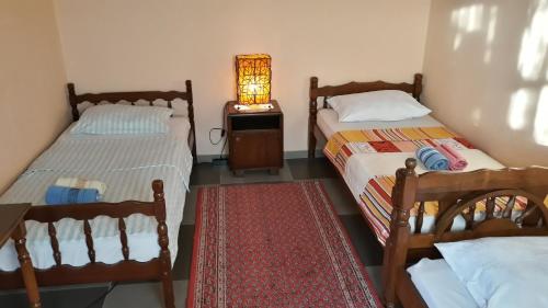 two beds in a room with a lamp on a table at Pensions Airport in Podgorica