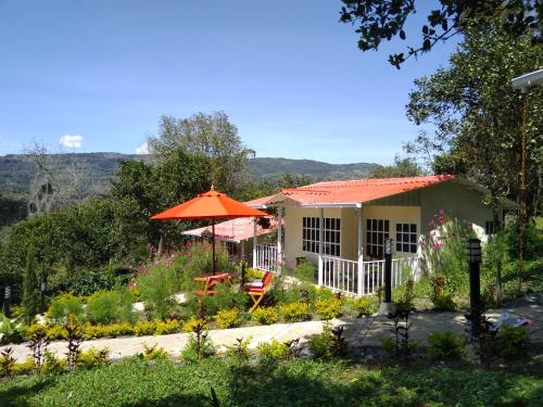 a house with an umbrella and a garden at Hostal Fisterra in Moniquirá