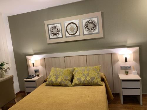 a bedroom with a bed with two tables and two plates on the wall at Hotel Herreros in Castellón de la Plana