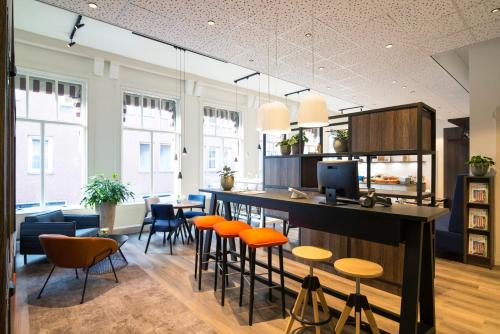 uma cozinha com cadeiras laranja e um bar num quarto em ibis Styles Den Haag City Centre em Haia