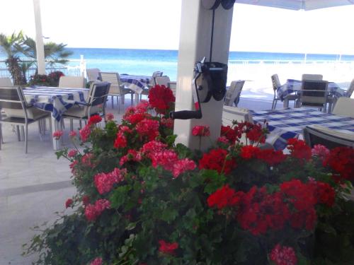 a patio with tables and flowers on the beach at Hotel Neva in Podstrana