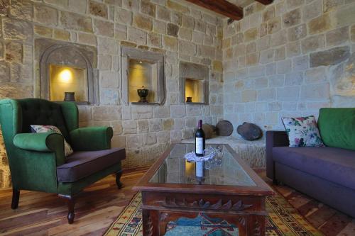 a living room with two chairs and a table with a bottle of wine at Panoramic Cave Hotel in Goreme