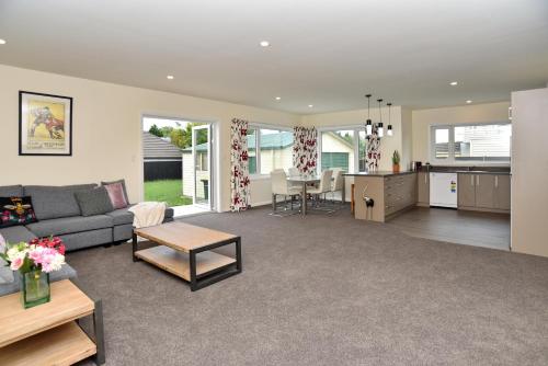 a living room and kitchen with a couch and a table at Weston Villa - Spacious & family Friendly - Bookahome in Christchurch