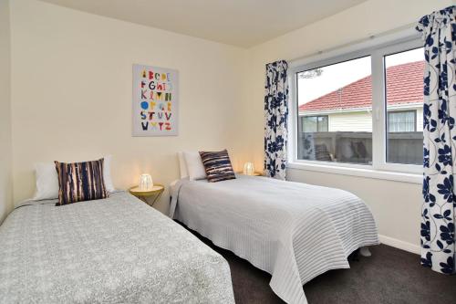 a bedroom with two beds and a window at Weston Villa - Spacious & family Friendly - Bookahome in Christchurch