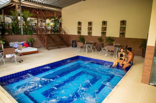a man and a woman sitting next to a swimming pool at Pousada Sítio Ipê in Viçosa do Ceará