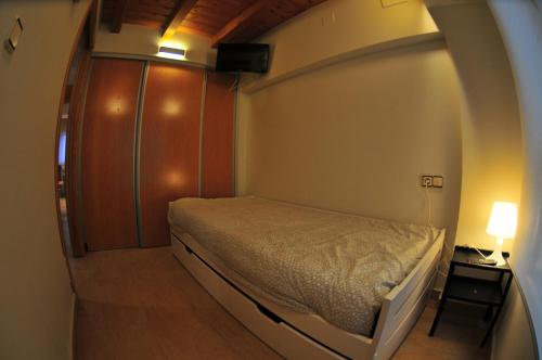 ein kleines Schlafzimmer mit einem Bett in einem Zimmer mit einer Lampe in der Unterkunft APARTAMENTOs URDAIBAI 1 in Bermeo
