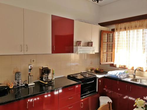 a kitchen with red cabinets and a black stove top oven at Myrto's Apartment No15 in Loutra Oraias Elenis