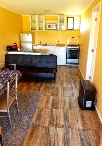 a living room with a couch and a kitchen at Aysen Bike Cabañas in Puerto Aisén