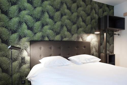 - une chambre avec un grand lit et du papier peint vert dans l'établissement Logis Hotel du Maine, à Laval