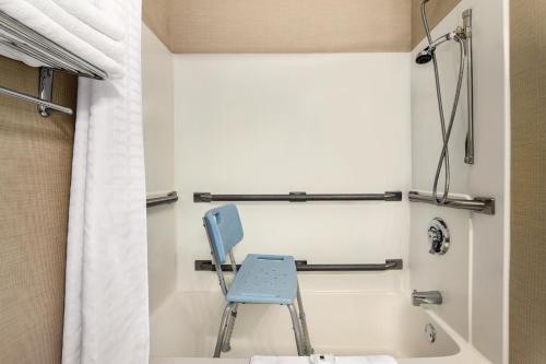 baño con ducha y silla azul en Country Inn & Suites by Radisson, Dakota Dunes, SD, en Dakota Dunes