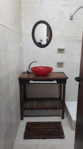 baño con lavabo rojo y espejo en cabaña las casuarinas en San Clemente del Tuyú