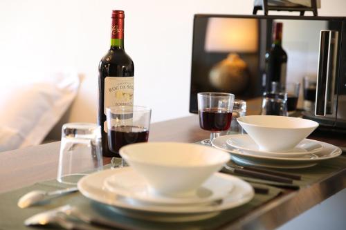 a table with a bottle of wine and plates and glasses at StandingAppart Marmande Centre in Marmande