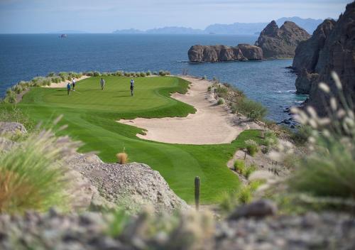 two people playing on a golf course near the ocean at Villa del Palmar at the Islands of Loreto in Loreto