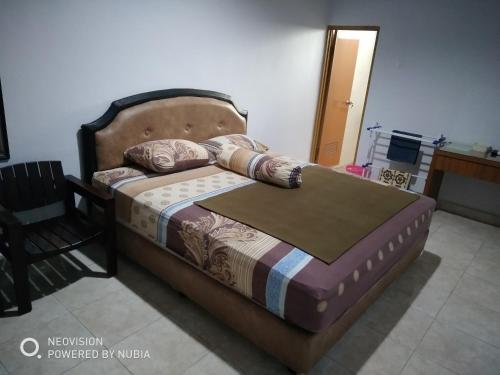 a bedroom with a bed with a wooden headboard and a chair at Rumah Retret Bethania in Kuta