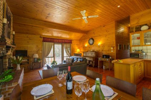 a kitchen and living room with a table with wine glasses at Silky Oak Cottage in Pokolbin