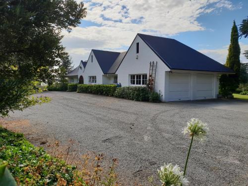 um celeiro branco com um telhado preto e uma entrada em Whiteacres em Invercargill