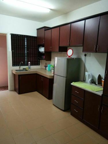 uma cozinha com armários castanhos e um frigorífico de aço inoxidável em Homestay Mama Razzin em Kuala Kangsar