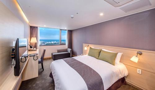 a hotel room with a large bed and a television at Hotel Shalom Jeju in Jeju
