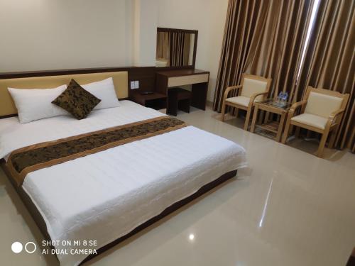 a bedroom with a bed and a desk and chairs at Ngọc Anh Hotel in Ha Long